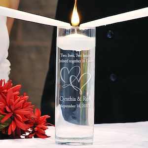 May include: A clear glass cylinder vase with water and a floating candle. The vase is engraved with the text "Two lives, Two hearts Joined together in Love" and "Cynthia & Ron September 14, 20XX".
