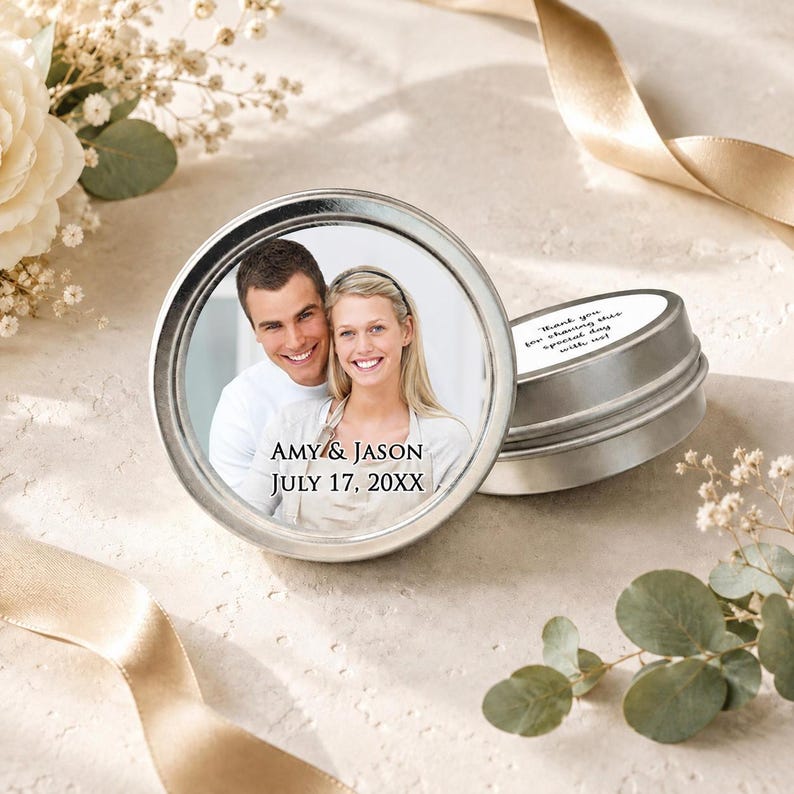 Puede incluir: Dos latas redondas de metal plateado con tapas. La tapa superior presenta una fotograf&iacute;a circular de una pareja sonriente con el texto impreso AMY & JASON JULY 17, 20XX. El lateral de la segunda tapa muestra el texto Thank you for sharing this special day with us!