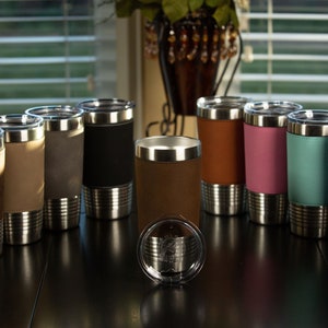 May include: A set of ten stainless steel tumblers with a variety of colored faux leather wraps. The tumblers have a double-wall construction and are insulated to keep drinks cold or hot.
