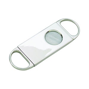 May include: A shiny, silver cigar cutter with a rectangular body and two rounded finger holes. The cutter features a circular blade in the center, designed for a clean cut. The tool is made of polished metal, reflecting light.