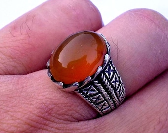 May include: A silver ring with an orange gemstone set in a detailed, ornate design.