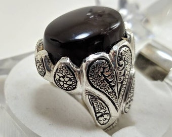 May include: A silver ring with an ornate design and a black onyx stone.
