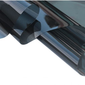 May include: A roll of dark grey window tint film. The film is rolled up and has a slight curve to it. The film is designed to block out heat and UV rays.