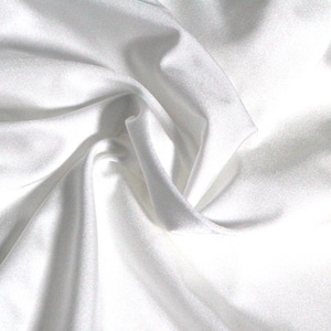 Puede incluir: Primer plano de una tela de satén blanco con pliegues suaves y un brillo lustroso. La tela parece suave y fluida, con reflejos y sombras que crean profundidad. El material se utiliza probablemente para ropa o decoración del hogar.