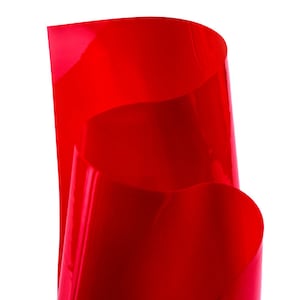 Peut inclure: Une feuille de vinyle rouge vif avec une finition brillante. Le vinyle est plié en deux et les bords sont incurvés.