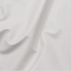 Puede incluir: Una tela blanca sólida con una textura suave y mate. El material está drapeado en pliegues suaves y delicados que crean sombras y reflejos sutiles en la superficie, destacando el color limpio y uniforme y la fluidez del tejido.