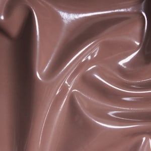 Könnte beinhalten: Nahaufnahme eines glatten, glänzenden, braunen Stoffes mit einem dezenten Schimmer. Der Stoff ist drapiert und gefaltet und erzeugt weiche Kurven und Falten.