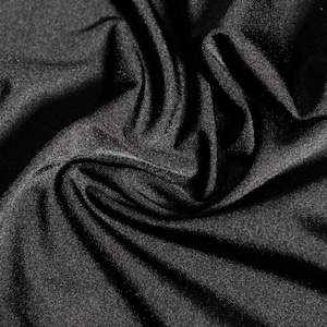 Puede incluir: Primer plano de una tela gris oscuro con una superficie suave y texturizada. La tela está drapeada y doblada, creando sombras y reflejos que enfatizan su textura y profundidad. El material parece ser un tejido de punto o tejido.