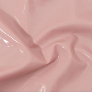 May include: Close-up of a glossy, pale pink material with subtle folds and highlights. The surface reflects light, creating a smooth, shiny appearance. The fabric has a soft, delicate color.