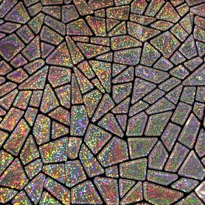 以下が含まれることがあります： 小さな不規則な形をした幾何学模様の銀色の虹色の生地。生地はキラキラと輝く仕上げになっています。