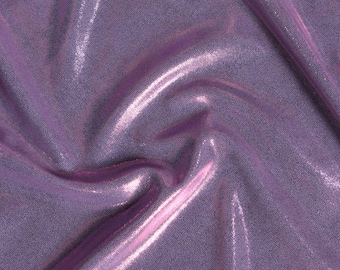 Könnte beinhalten: Nahaufnahme eines schimmernden, lavendelfarbenen Stoffes mit einer strukturierten, gepunkteten Oberfläche. Das Material ist gefaltet, wodurch Glanzlichter und Schatten entstehen, die seine reflektierende Qualität hervorheben. Der Stoff hat ein weiches, fließendes Aussehen.