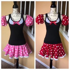 May include: Two Minnie Mouse inspired dresses with black tank tops, white collars, red bows, and puffy sleeves. One dress has a pink polka dot skirt with white polka dots and the other has a red polka dot skirt with white polka dots.