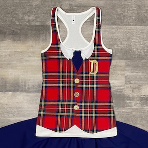 May include: A red plaid tank top with a white collar and a gold letter "D" on the front. The tank top has a white racerback design and is paired with a navy blue skirt. The vest has three gold buttons.