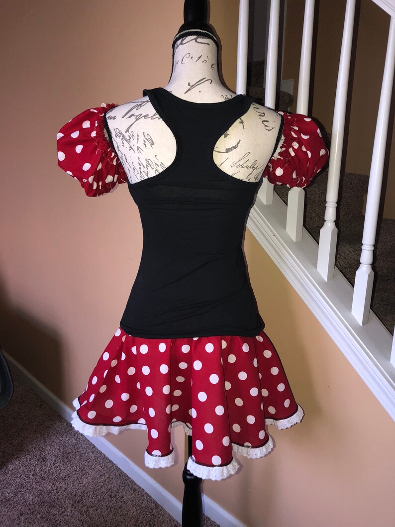 May include: A red and white polka dot dress with a black tank top. The dress has a white lace trim and puff sleeves.