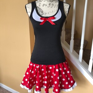May include: A black tank top with a white collar and a red bow. The tank top is paired with a red skirt with white polka dots and a white lace trim.