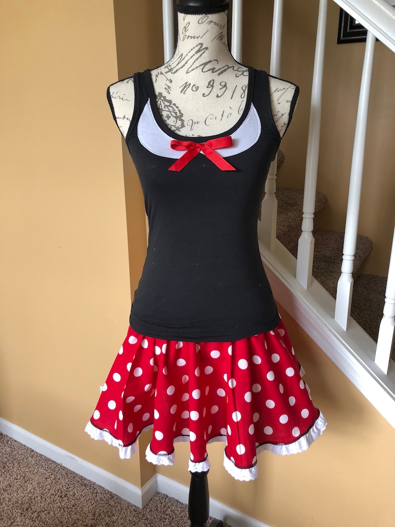 May include: A black tank top with a white collar and a red bow. The tank top is paired with a red skirt with white polka dots and a white lace trim.