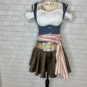 May include: A blue denim corset with a white peasant top and brown skirt. A red and white striped sash is tied around the waist with a gold buckle.
