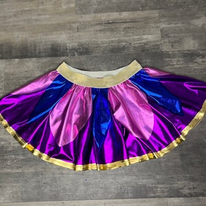 May include: A purple, pink, and blue iridescent skirt with a gold trim. The skirt is made of a shiny fabric and has a gathered waistband.