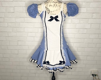 May include: A blue and white dress with a black and white checkered trim. The dress has a white apron with black trim and black bows. The dress is on a black mannequin.