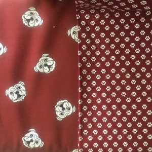 May include: Two fabric swatches, one with a red background and white bulldog faces, the other with a red background and white paw prints.