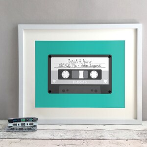 May include: A framed print of a cassette tape with the text "Sarah & Lewis All Of Me - John Legend 11-08-16" on a teal background.