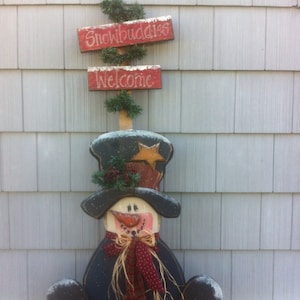 Könnte beinhalten: Eine Schneemann-Dekoration aus Holz mit einem schwarzen Zylinder, einem roten Schal und einem Schild mit der Aufschrift "Snowbuddies" und "Welcome".