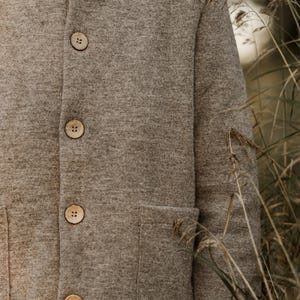May include: A brown hooded jacket with a button closure and a patch pocket. The jacket is made of a soft, fuzzy material.