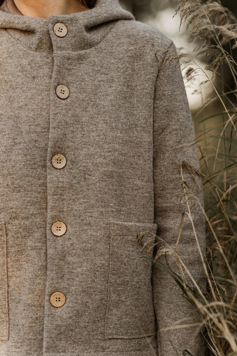 May include: A brown hooded jacket with a button closure and a patch pocket. The jacket is made of a soft, fuzzy material.
