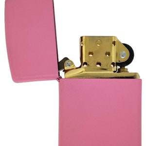 May include: A pink lighter with a gold hinge and a gold top. The lighter is open and the lid is flipped back.