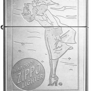 May include: Silver Zippo windproof lighter with an engraved design. The design features a woman in a flowing dress, with stars and a moon in the background. The lighter has the words "Wind-Proof Zippo Lighter" in a circular emblem.