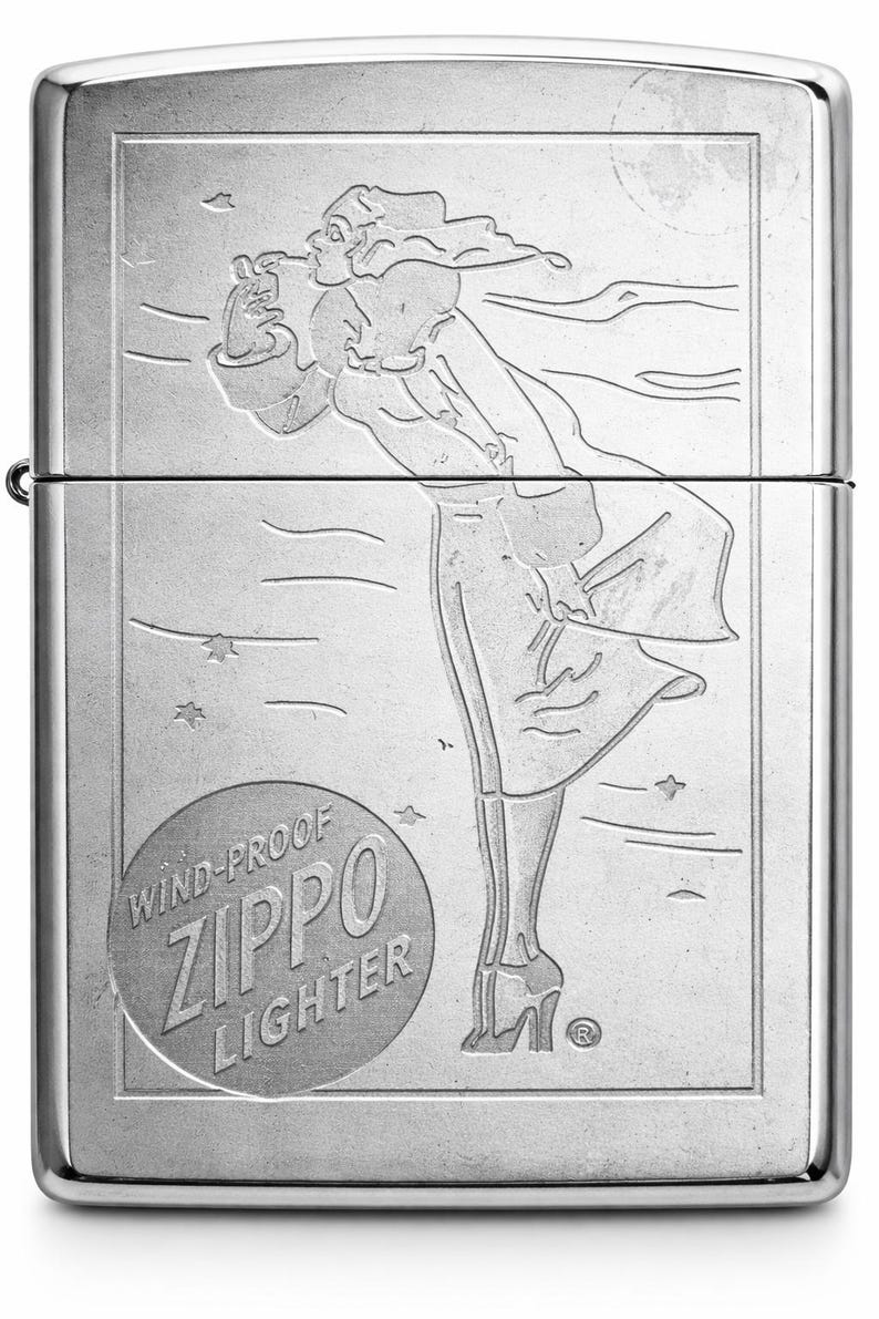 May include: Silver Zippo windproof lighter with an engraved design. The design features a woman in a flowing dress, with stars and a moon in the background. The lighter has the words "Wind-Proof Zippo Lighter" in a circular emblem.