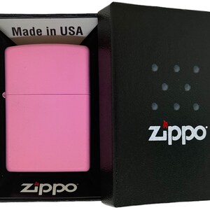 May include: A pink Zippo lighter in a black box with the Zippo logo and the words "Made in USA".