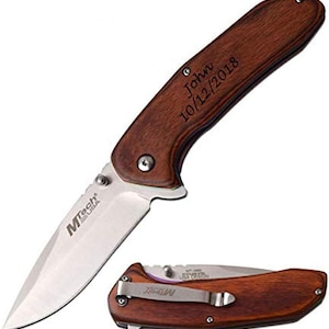 May include: A folding pocket knife with a wooden handle. The blade is silver and the handle is engraved with the name "John" and the date "10/12/2018". The knife is labeled "MTech USA".