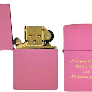 May include: A pink lighter with a gold hinge and a gold top. The lighter has a blank space on the front for personalization. The text on the lighter reads "Add your text here Upto 5 lines and 30 letters per line".