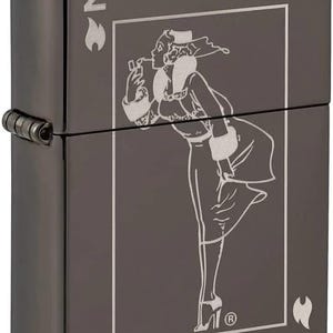 May include: Gunmetal-colored lighter with a detailed engraved design. The design features a woman in a vintage outfit, smoking a cigarette. The lighter has the letter "N" and a flame symbol on the sides.