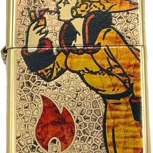 May include: A gold-colored lighter with a detailed illustration. The design features a figure in yellow and black attire, smoking a pipe, set against a textured background. A red flame graphic is at the bottom.