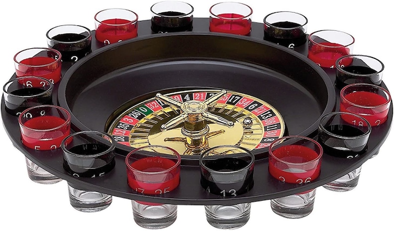 Puede incluir: Un juego de ruleta negro con 16 vasos de chupito dispuestos alrededor de la rueda. La rueda tiene los n&uacute;meros del 1 al 36, 0 y 00. Los vasos de chupito son transparentes con fondos rojos y negros.