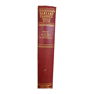 May include: A red hardcover book with gold lettering. The title is "Harvard Classics Shelf of Fiction". The authors listed are Balzac, Sand, de Musset, Daudet, and de Maupassant. The number "13" and the word "Collier" are also printed on the book.