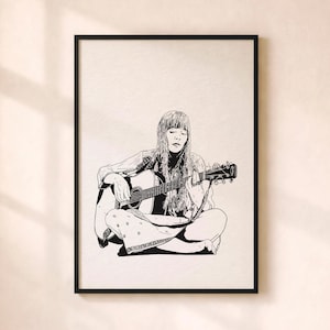 May include: A monochrome framed print depicting a person seated and playing an acoustic guitar. The artwork is a detailed line drawing, showing the musician's clothing and long hair. The frame is black, and the background is a neutral colour.