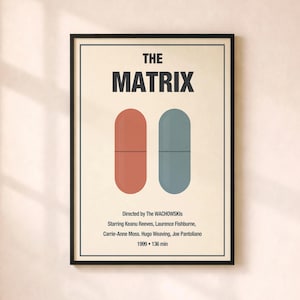 May include: A framed poster for the movie "The Matrix." The poster features the title in bold black letters above two pill shapes, one red and one blue. Below, the names of the director and cast are listed.