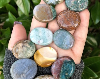 May include: A collection of 10 smooth, polished, oval-shaped stones with various patterns of green, brown, white, and blue. The stones are arranged in a hand.