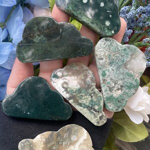 May include: Five green moss agate cloud shaped stones. The stones are various shades of green and white with a cloudy, marbled pattern.