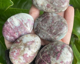 May include: Five smooth, polished, oval-shaped stones with a white base and pink and gray swirls and speckles.