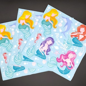 May include: Four blue sheets with mermaid illustrations. Each sheet features a different mermaid with a different colored tail and hair. The text "Mermaids are real" is printed on one of the sheets.