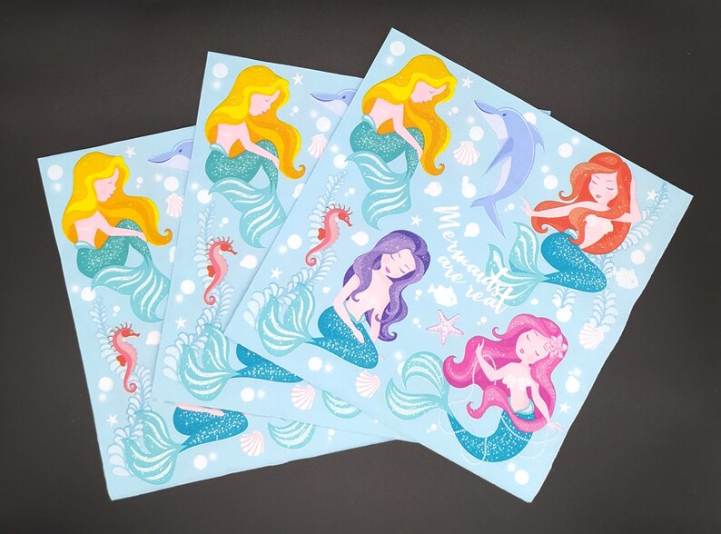 May include: Four blue sheets with mermaid illustrations. Each sheet features a different mermaid with a different colored tail and hair. The text "Mermaids are real" is printed on one of the sheets.