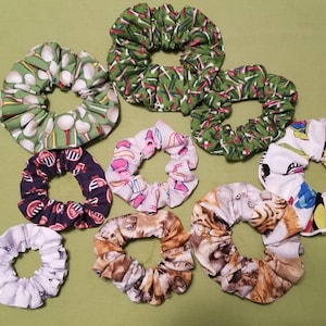 May include: Ten colorful fabric scrunchies with various patterns, including golf balls, animals, and abstract designs.