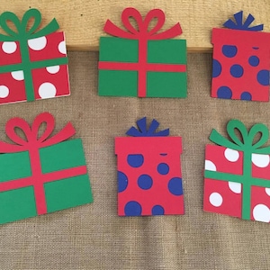 May include: Six paper cutouts of Christmas presents in various colors and patterns. The presents are red, green, and blue with white polka dots.