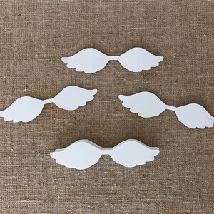 May include: Three sets of white paper angel wings. Each set is made of two wings connected in the center.