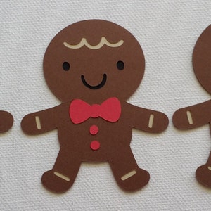 May include: Three brown gingerbread man cutouts with white icing details, red bow ties, and brown buttons.