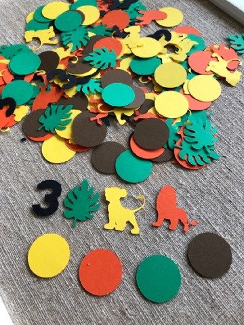 K&ouml;nnte beinhalten: Eine Sammlung bunter Papierkonfetti mit Dschungeltieren, Bl&auml;ttern und Kreisen in Gr&uuml;n-, Gelb-, Braun-, Orange- und Schwarzt&ouml;nen. Das Konfetti ist perfekt f&uuml;r eine Geburtstagsfeier oder andere Feierlichkeiten.